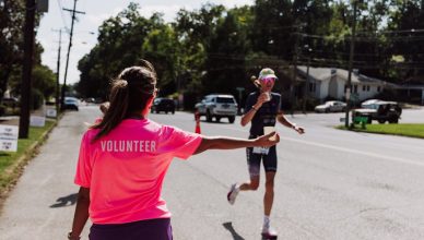 volunteer aiding marathon runner on sunny day